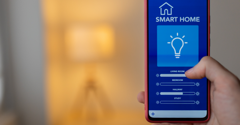 Slimme verlichting in huis: telefoon met bedieningsscherm en op de achtergrond een lamp die aan staat